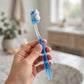 Hand holding a POH POH toothbrush with toothpaste — how to use