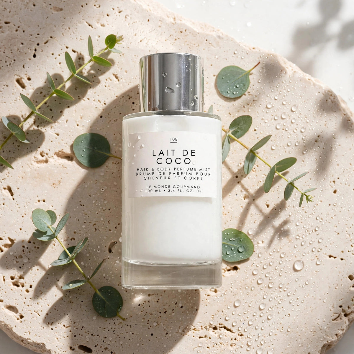 Le Monde Gourmand Lait de Coco Hair & Body Mist 100ml on travertine stone with eucalyptus - view 1